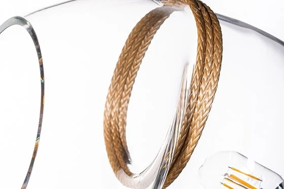 Close-up of three braided bangles on a clear glass surface with light reflecting off them.