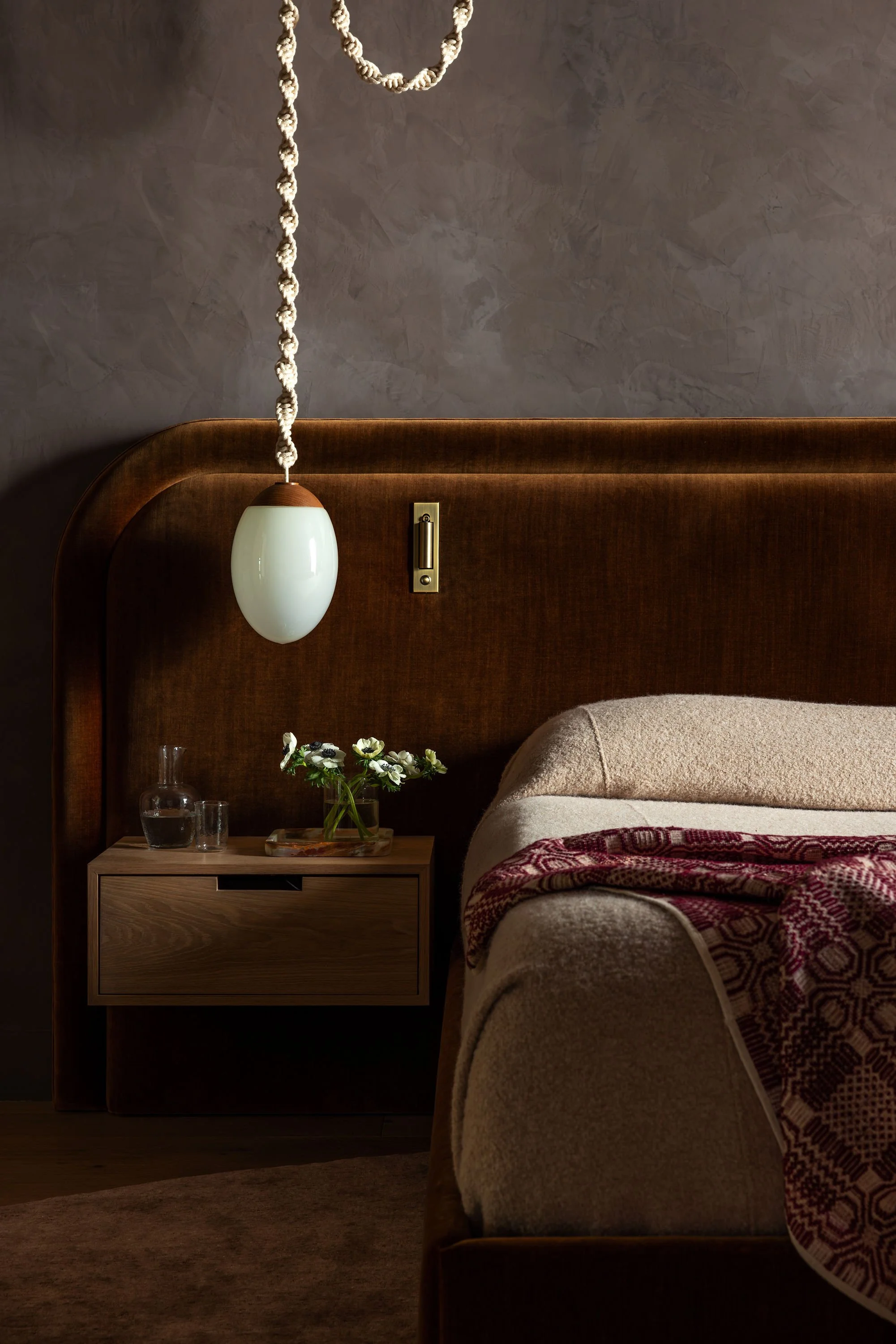 A bathroom with dark floral mural, round mirror, Brightbound Sila studio-blown pendant lighting, and stone sink on a wooden counter.