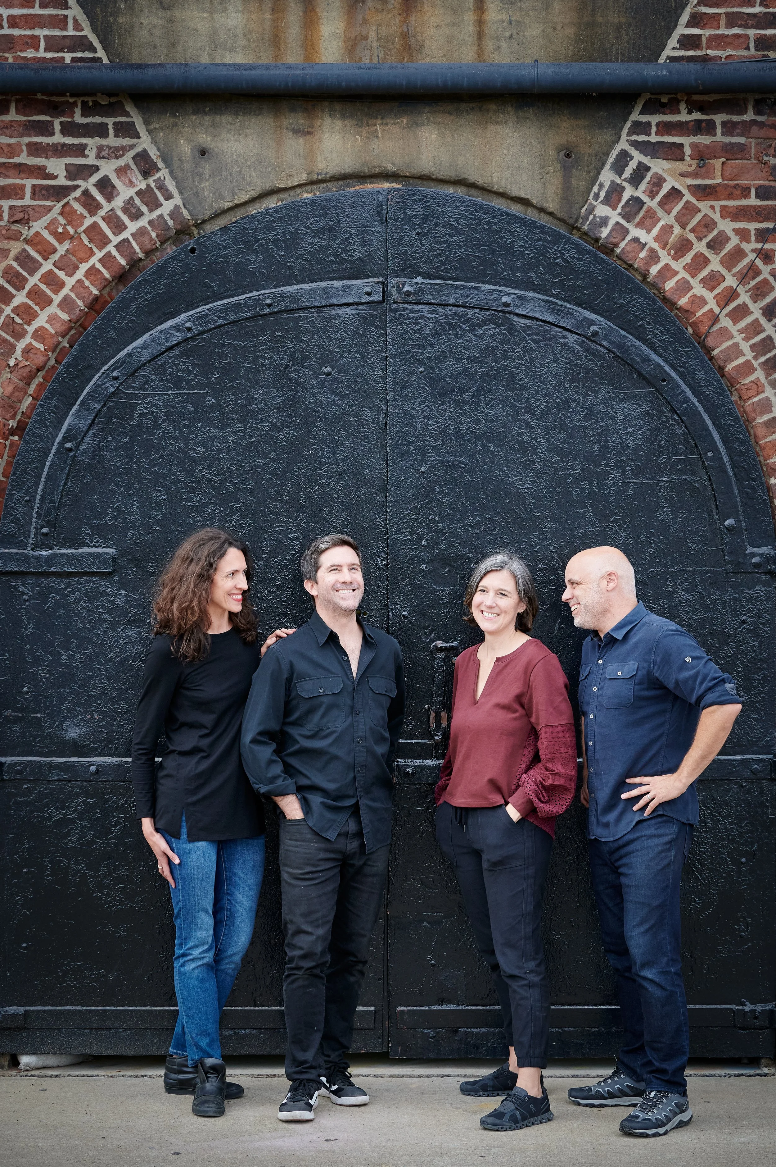 The Brightbound partners standing in front of an architecturally designed, arch doorway in a brick wall.