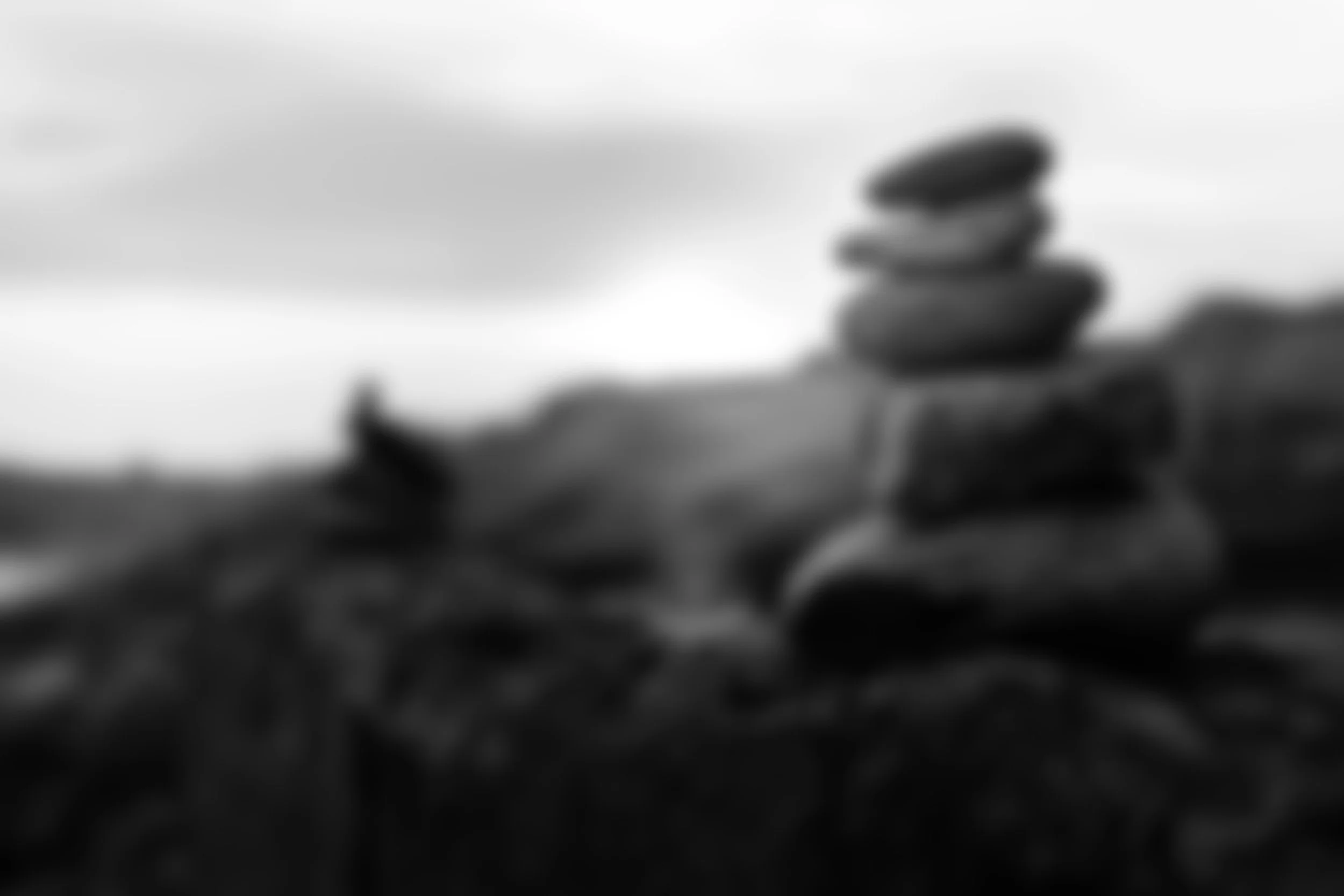 Blurred black-and-white photograph of a stack of stones on a natural outdoor landscape.