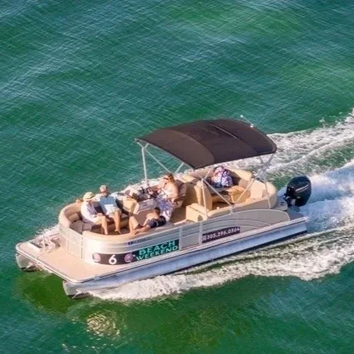 A group of people relaxing on a pontoon boat with a canopy, cruising on a body of water.
