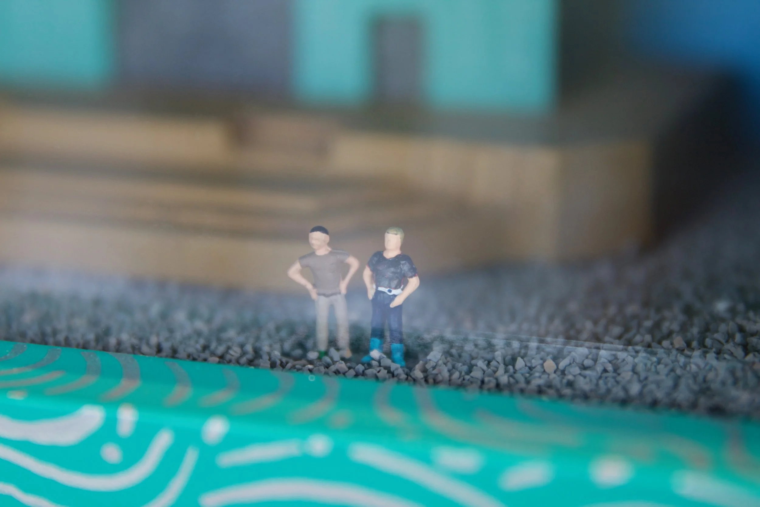 Slowpoke Studio’s website redesign for Wiseacre Brewing Company. Miniature figurines of two men stand on rocky ground, with a blurred background and a green surface with white lines in the foreground.