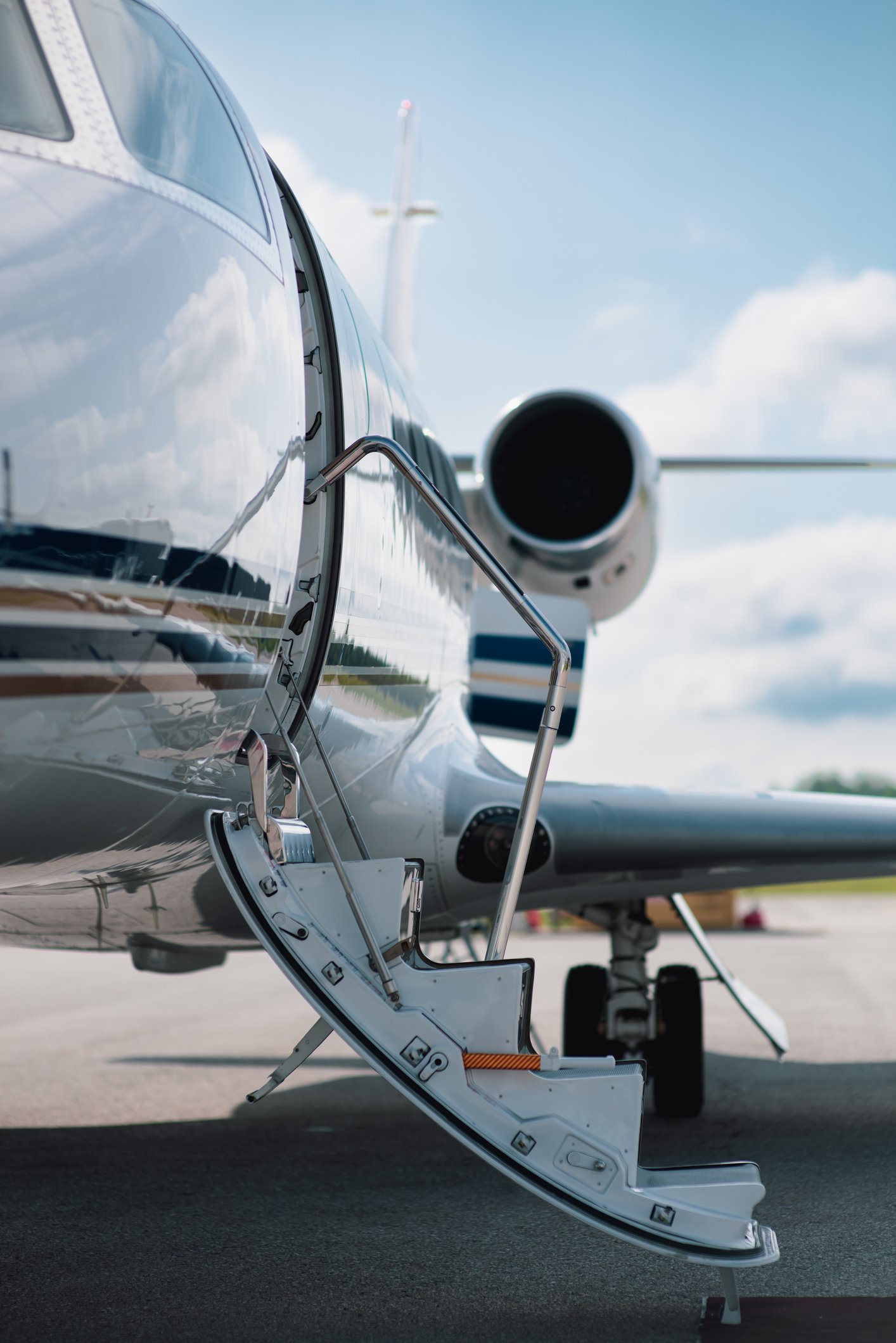 Close-up of the open entrance door of a private jet on the tarmac with the staircase extended.