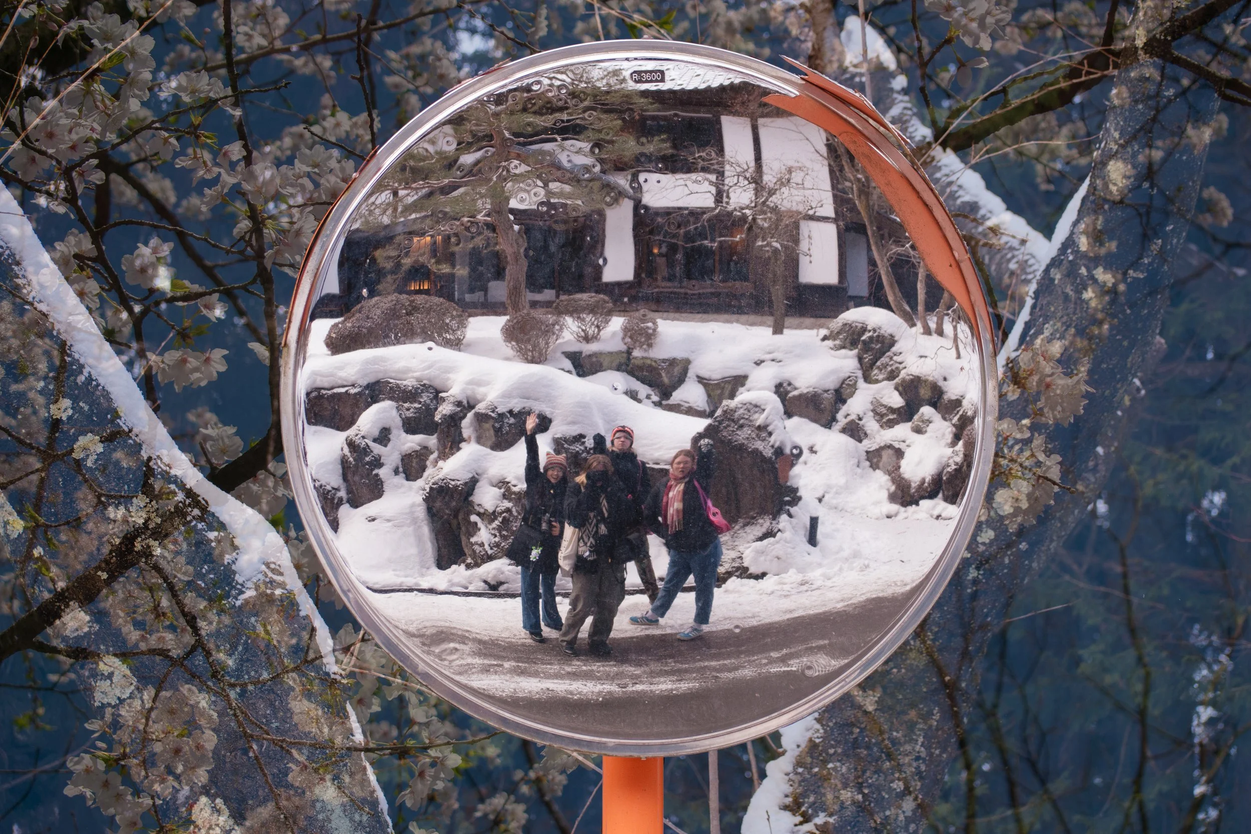 Japan double exposure film photo of street mirror with 4 individuals, overlaid with snowy trees.