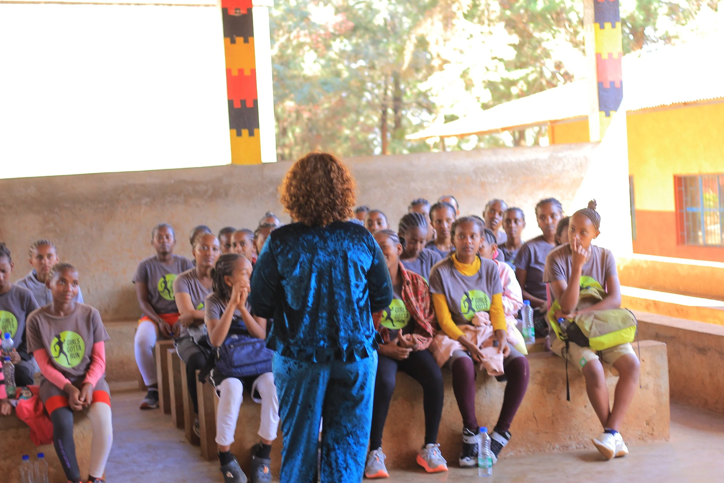 Woman in blue addressing the classroom of Athletic Scholars in their Girls Gotta Run shirts