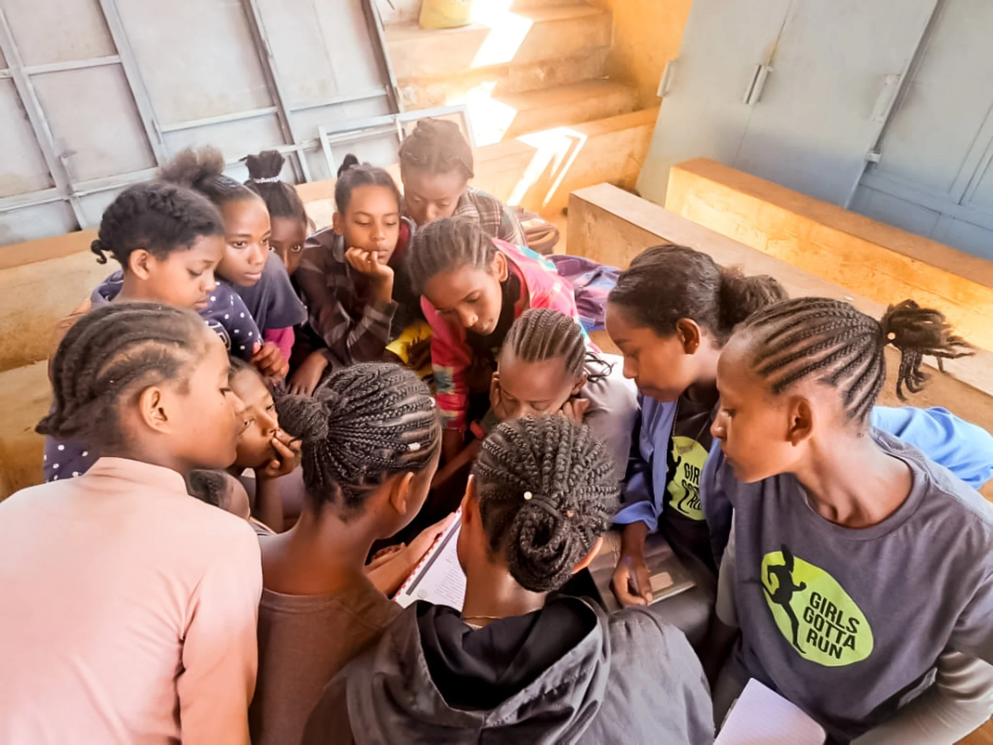 Ethiopian Athletic Scholars huddled together reviewing a book in a classroom