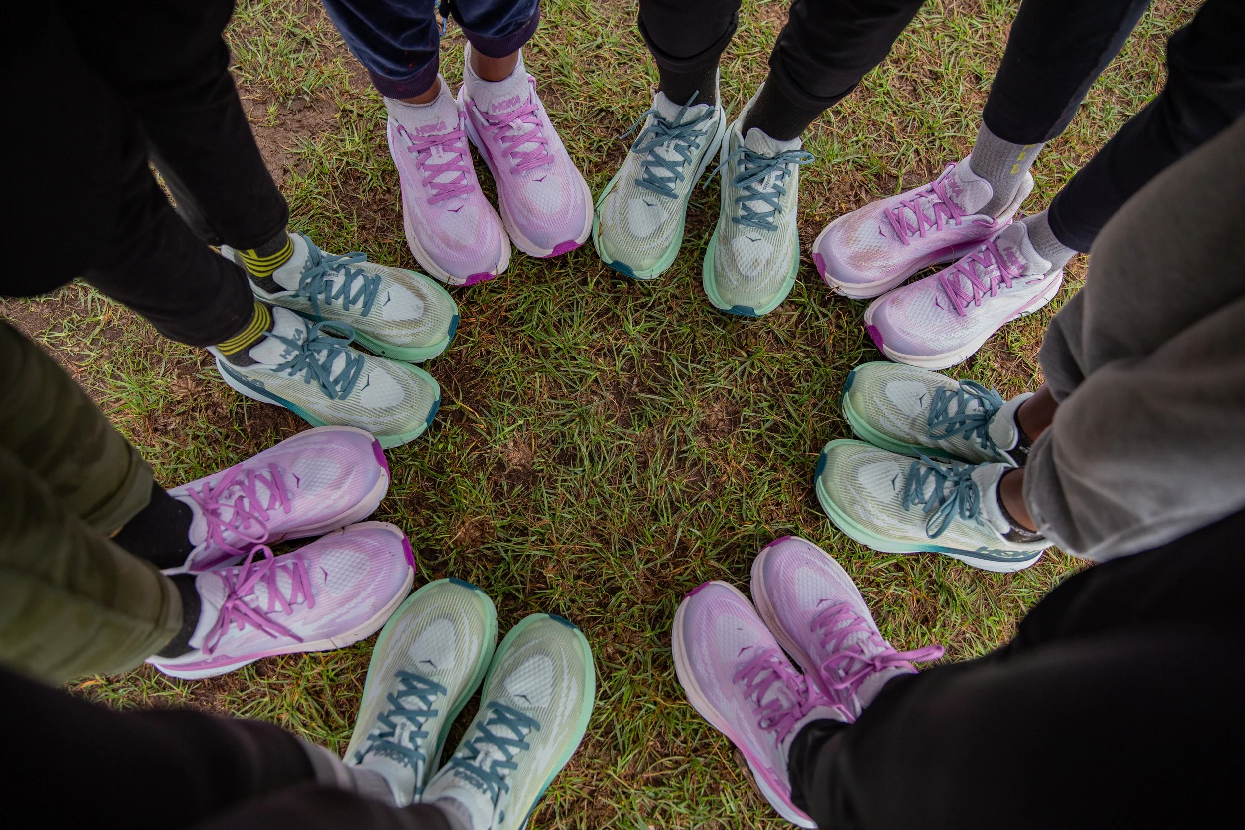 View of girls' feet wearing running shoes, standing in a circle, photo taken top down