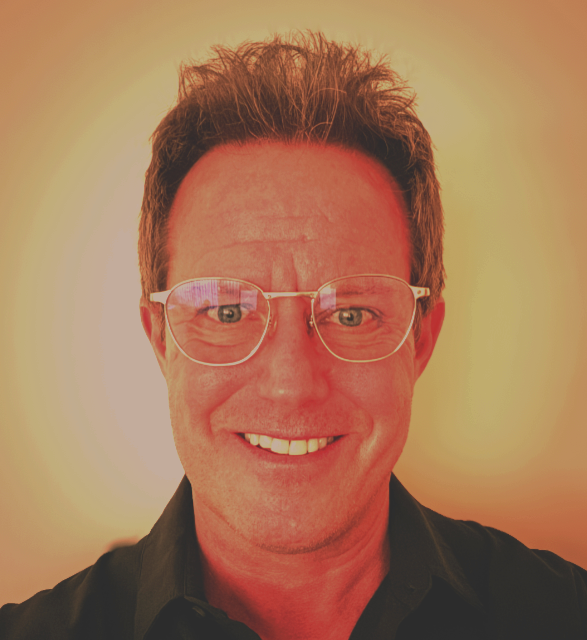Smiling man with curly brown hair, glasses, wearing a black shirt, in front of a yellow gradient background.