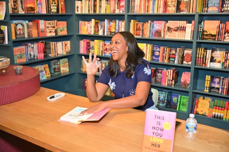 Traci laughing with a reader at the signing table at Kindred Stories
