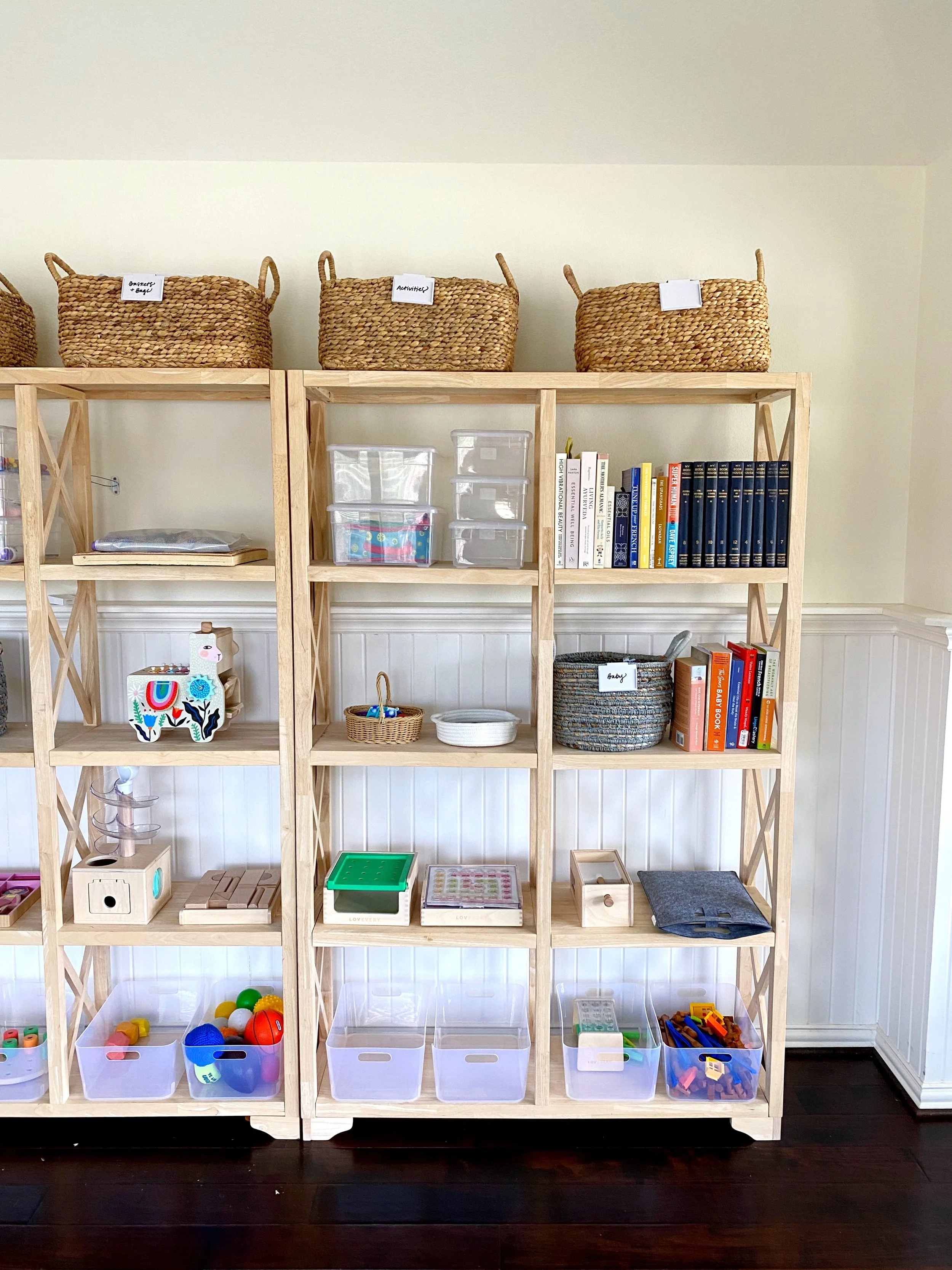 Wooden shelving unit filled with toys, books, and storage bins in a playroom.