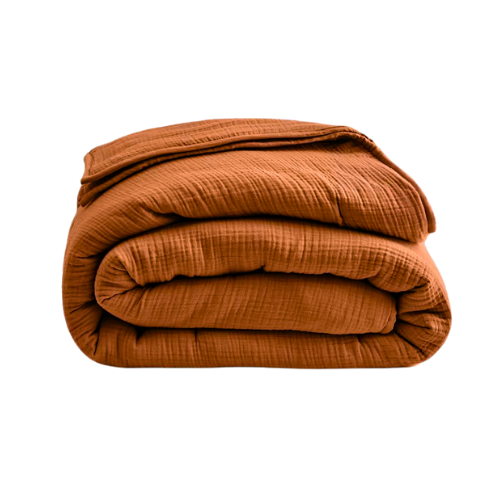 A neatly folded, orange-brown quilt or blanket on a black background.