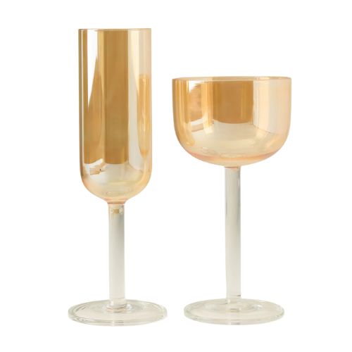 Two empty gold-colored wine glasses, one tall flute and one short goblet, on a plain background.