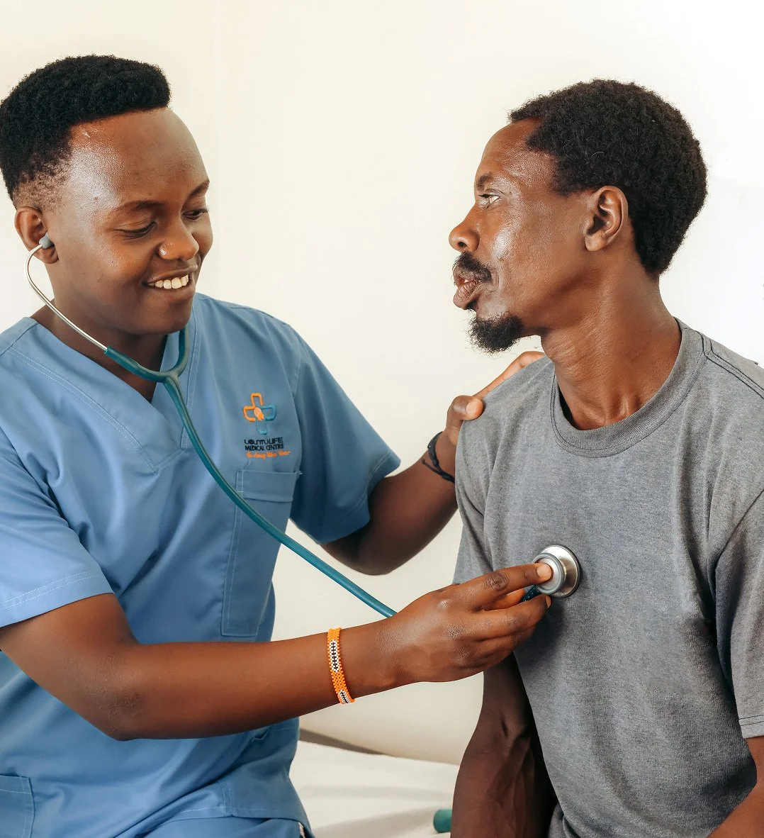 Medical professional using a stethoscope to examine a middle-aged man's chest.