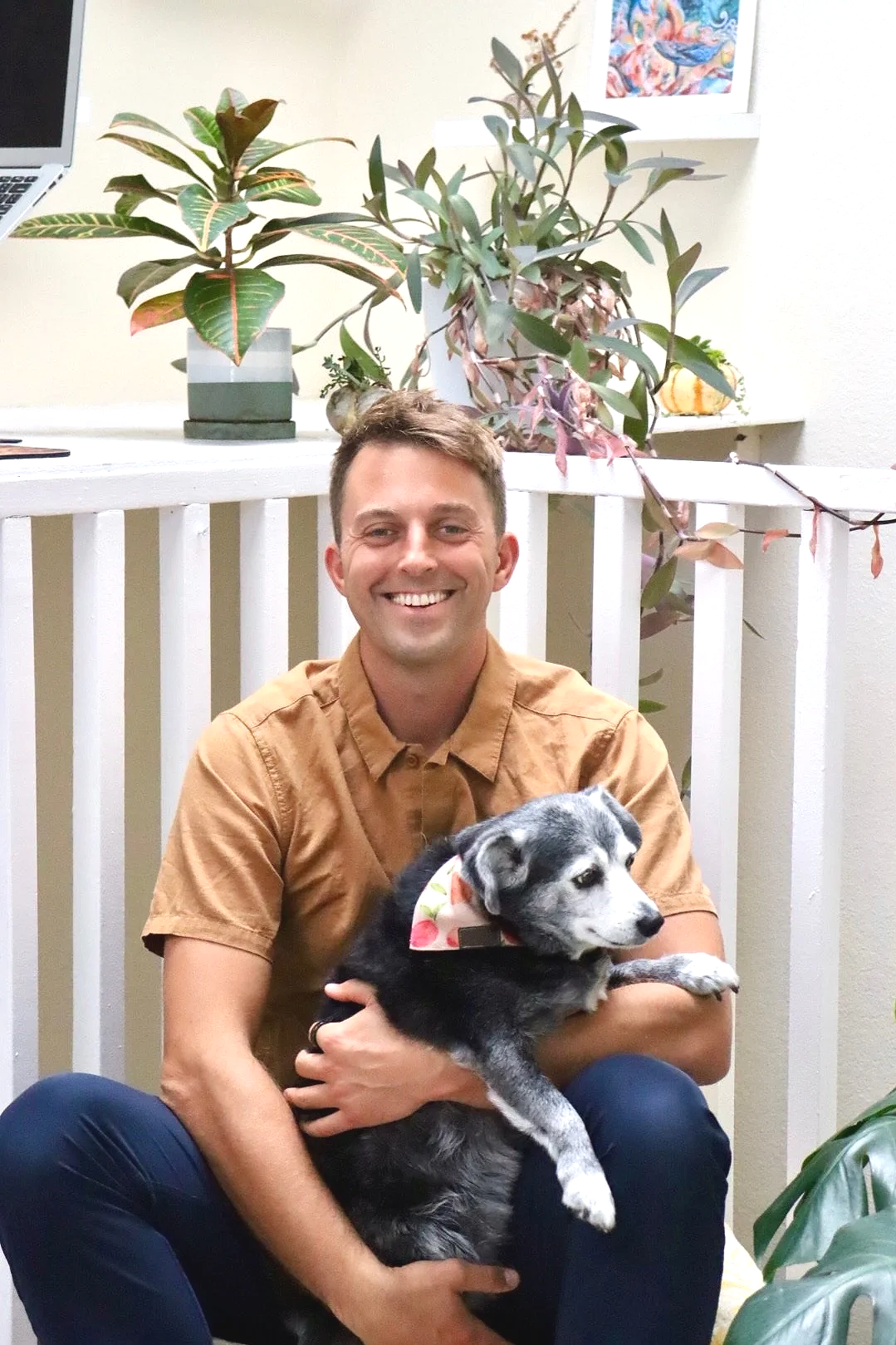 Dr. Joe Thompson, pediatric and perinatal chiropractor at Rhythm Health & Performance in Santa Cruz, smiling with his dog