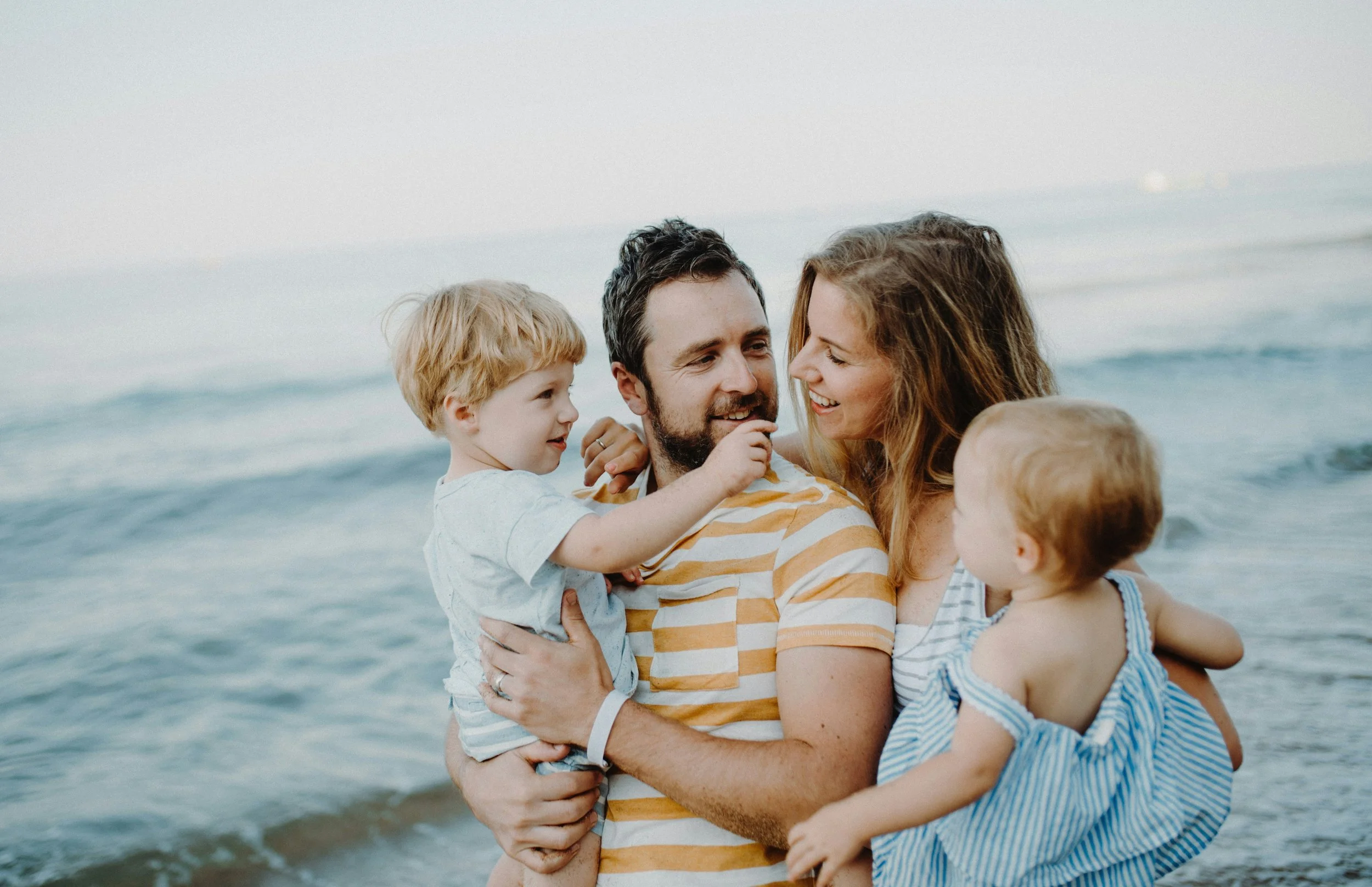 Happy family with two young children laughing together — pediatric chiropractic care for nervous system regulation and child development at Rhythm Health Santa Cruz Next!