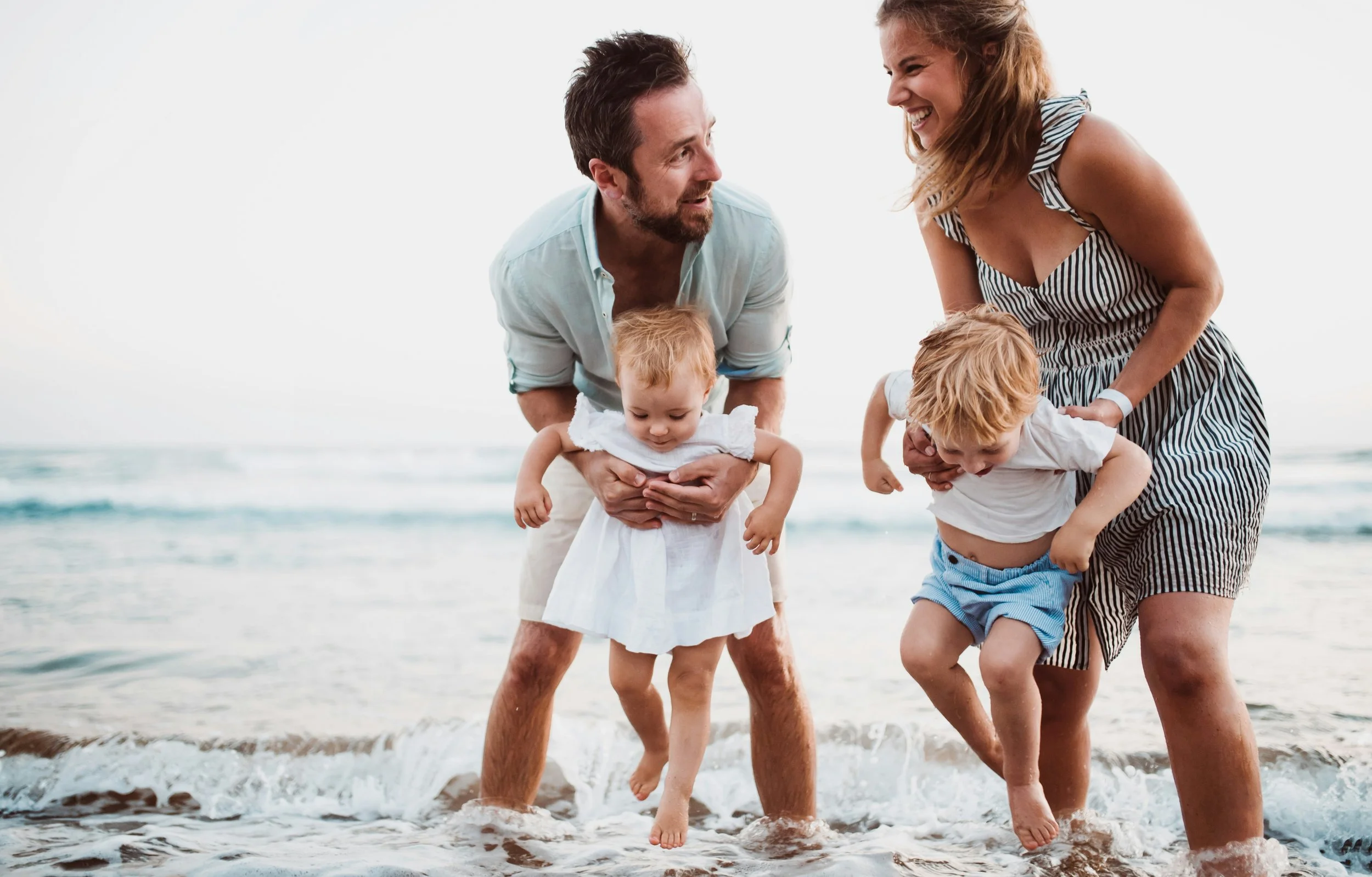 Happy young family on the beach — pediatric and family chiropractic care in Santa Cruz