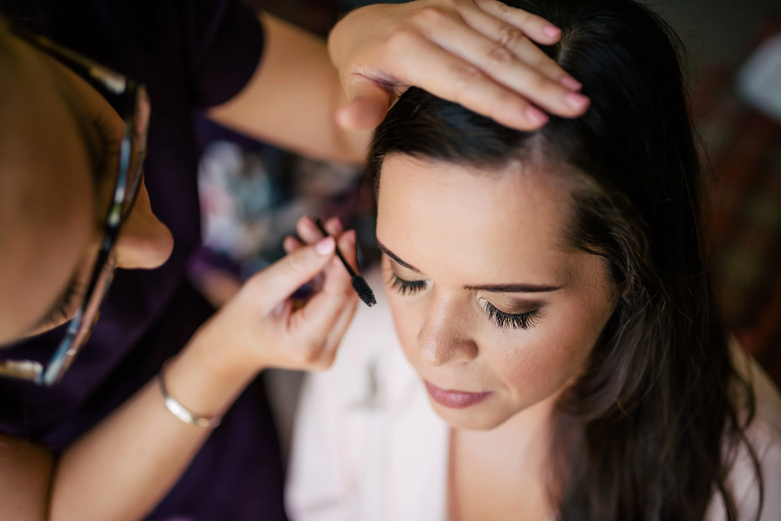 Makeup artist applying mascara to a woman with closed eyes