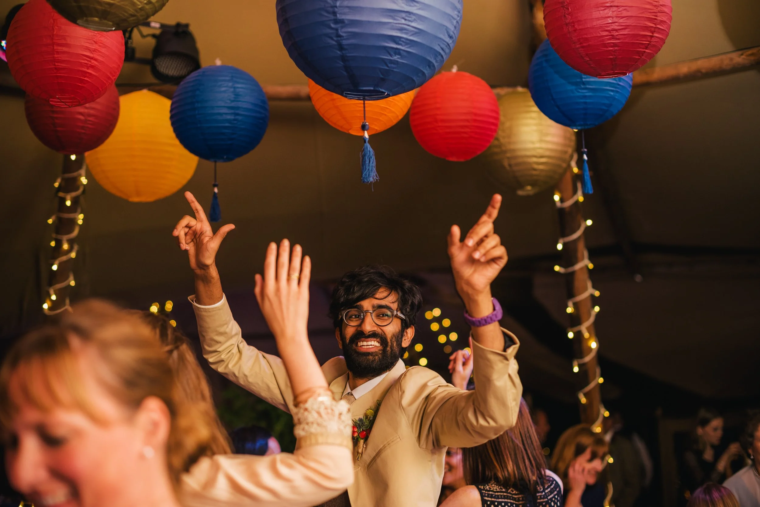 Man dancing at a celebration with colorful paper lanterns hanging overhead.