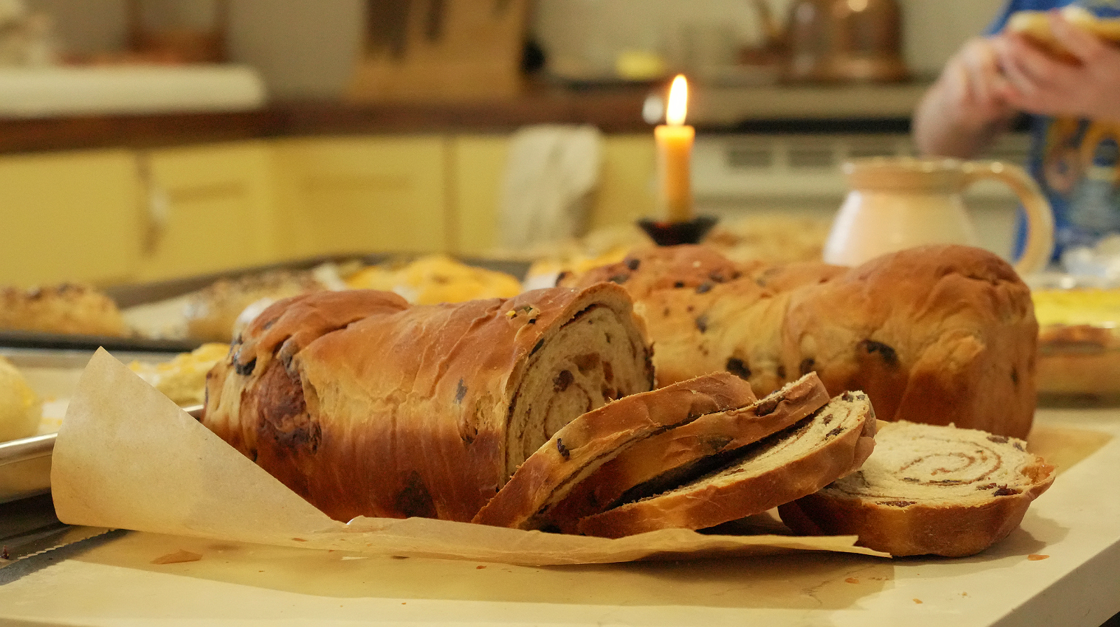 cinnamon swirl bread with raisins on parchment paper, amid lit candle