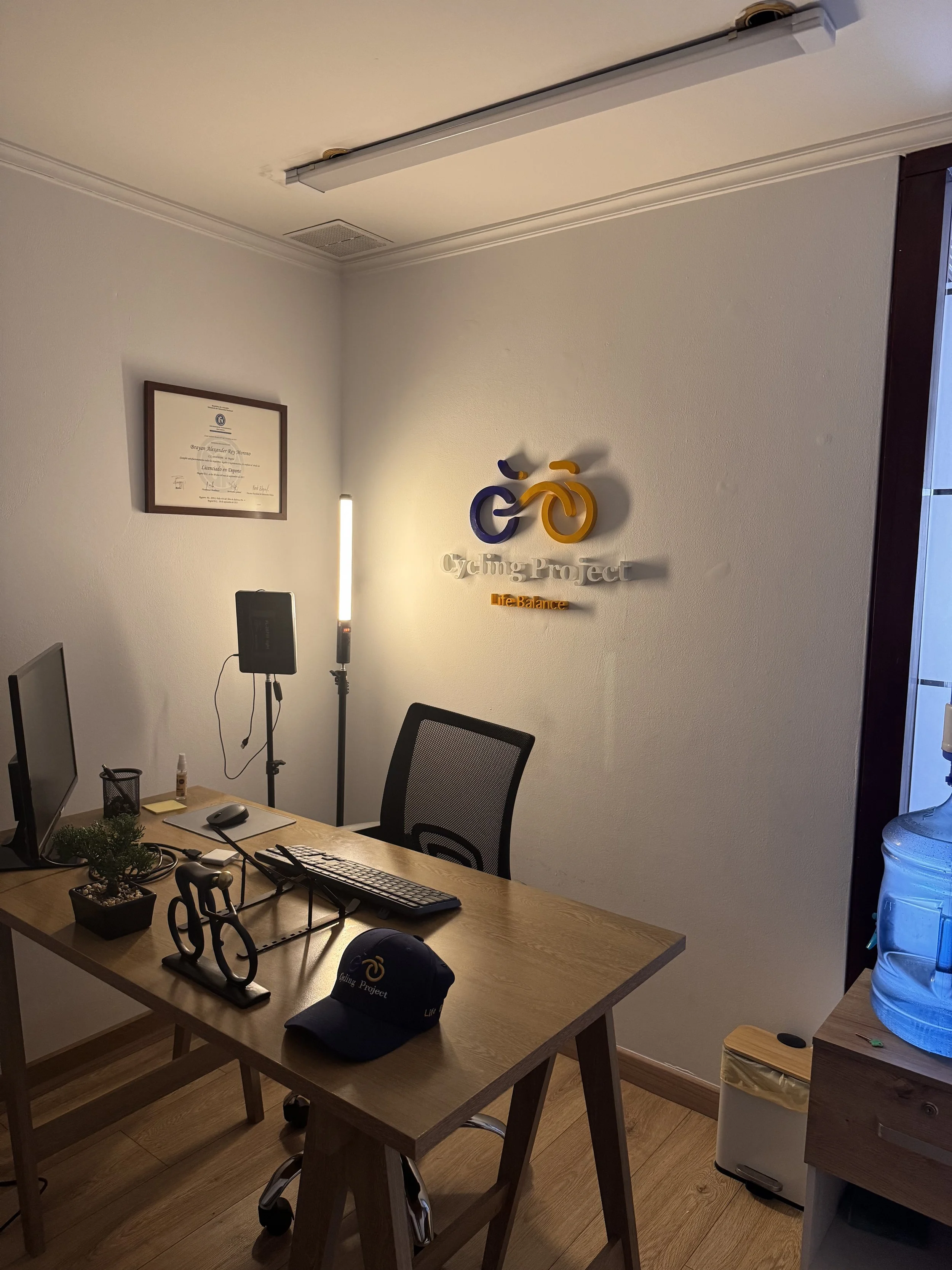 Oficina con mesa de madera, computadora, silla y varios objetos decorativos y de oficina.