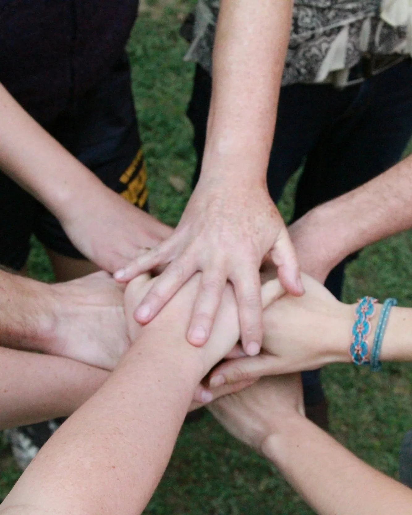 Groupe de plusieurs mains de différentes personnes placées les unes sur les autres, symbolisant l'unité et la collaboration.