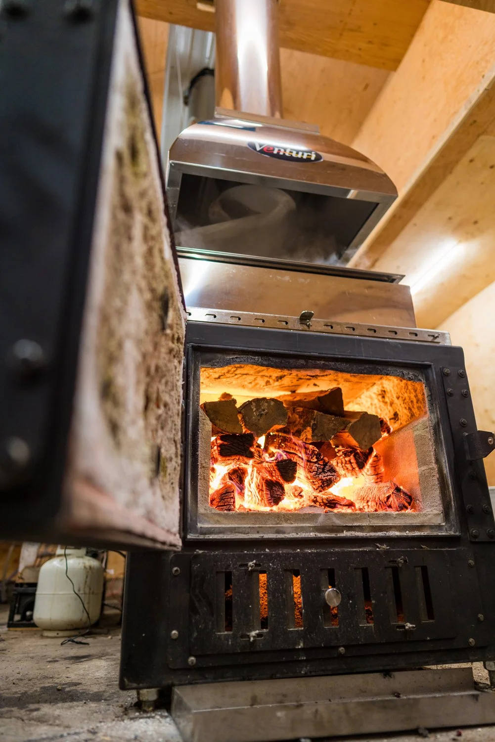 Process of maple maple syrup - showing the wood-burning syrup with glowing embers and burning logs inside. Milestone Ridge Maple Syrup - Pure Ontario maple syrup from Palmerston, Ontario, Canada. Grade A maple syrup available for purchase.