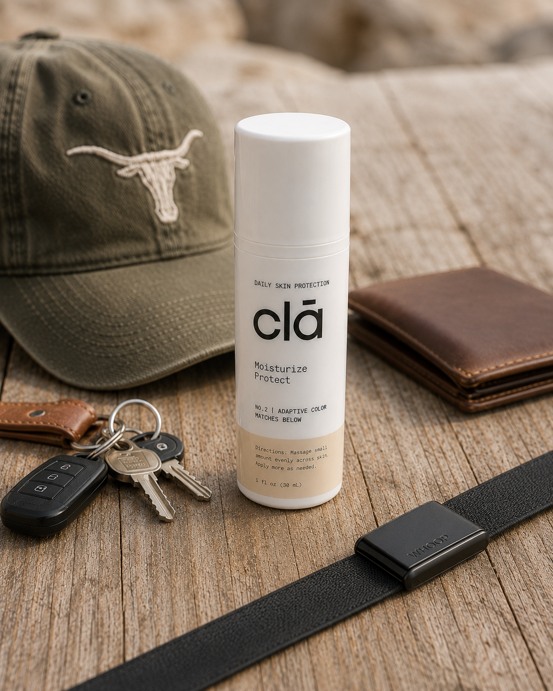 A white bottle of skincare moisturizer labeled 'clā' with 'Moisturize Protect' on a wooden surface. Nearby are a baseball cap with a longhorn logo, a set of car keys, a brown leather wallet, and a black wristwatch.