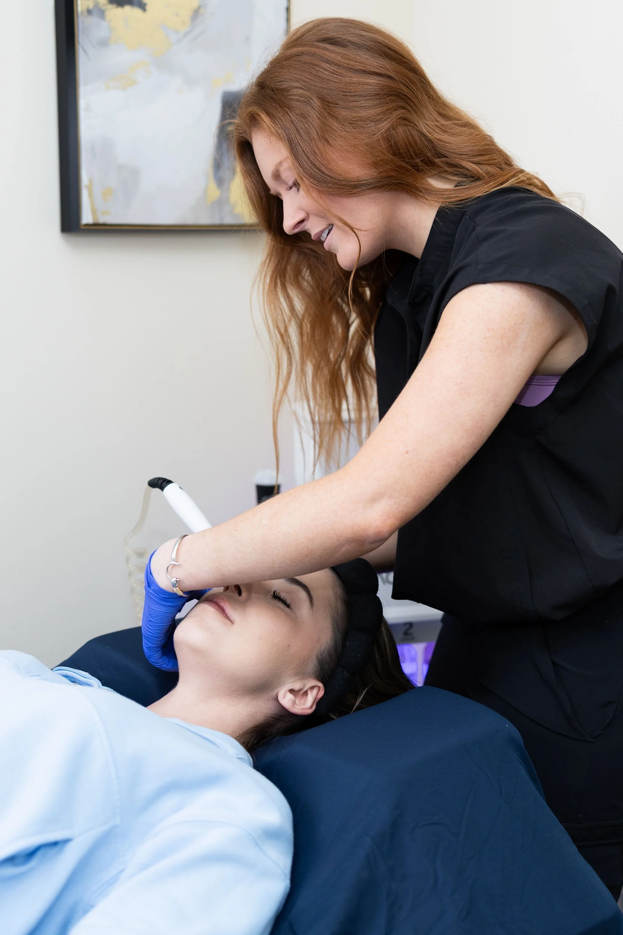 An aesthetic professional wearing gloves is performing a laser procedure on a patient at Revitalize Health Med Spa in Florence, South Carolina.