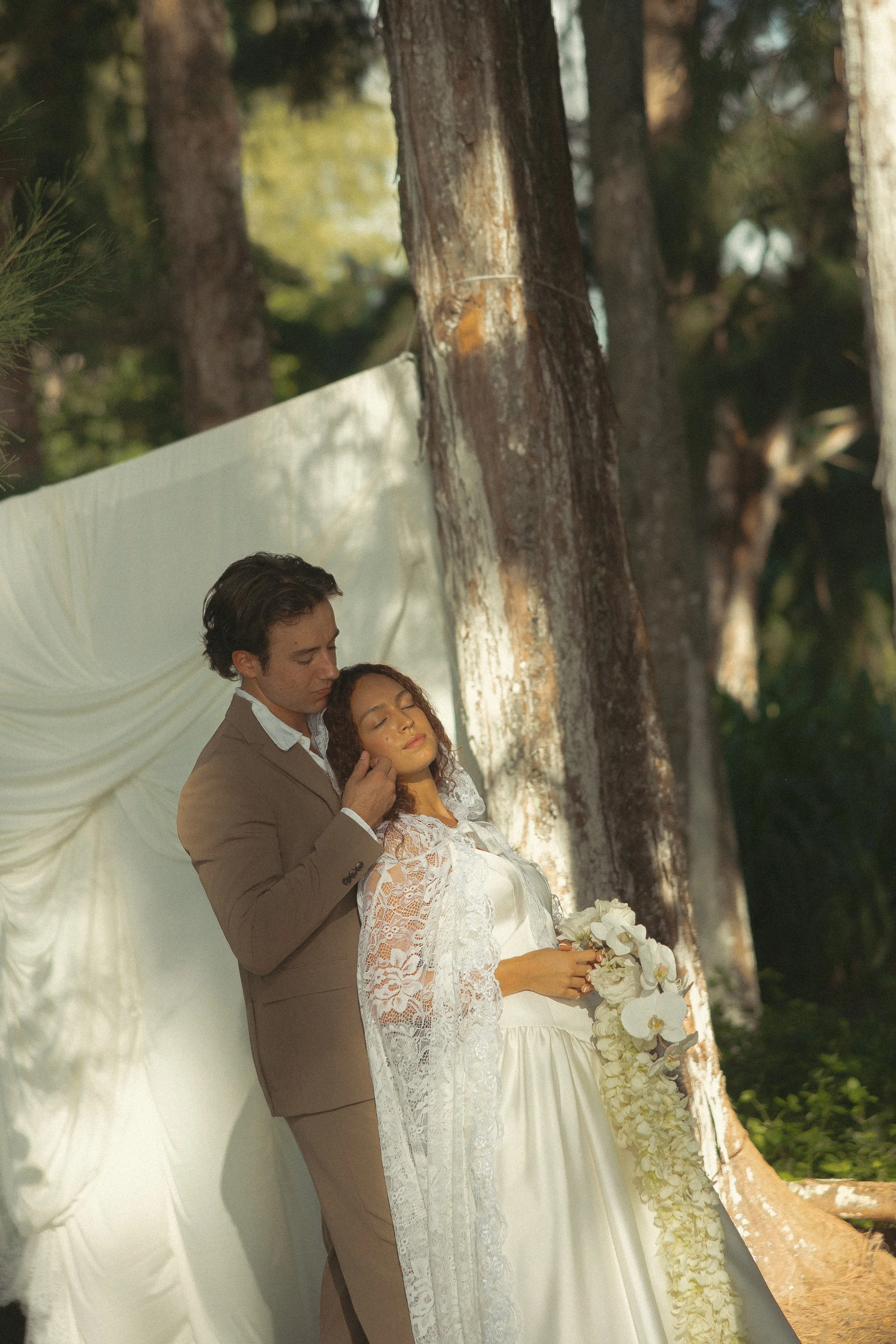 oahu-couple-embracing-white-draped-backdrop-lace-cape-maggie-t-photography