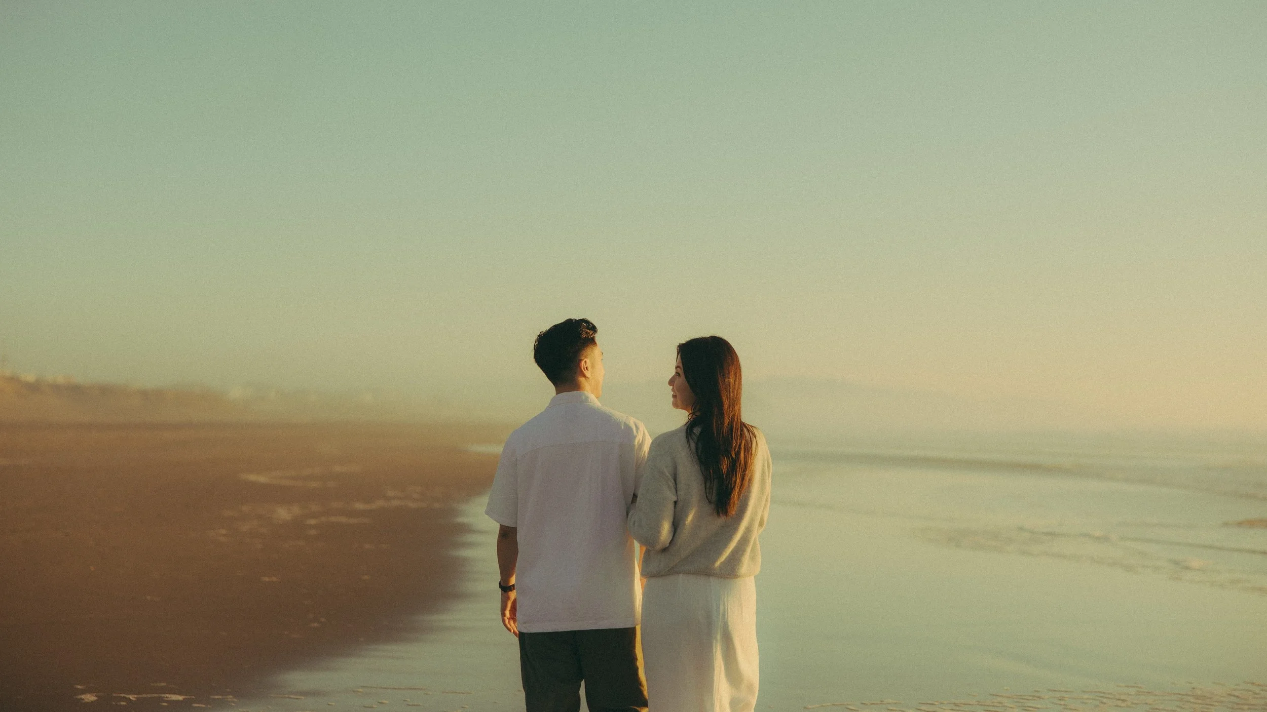 Oahu couples walking on beach at sunset