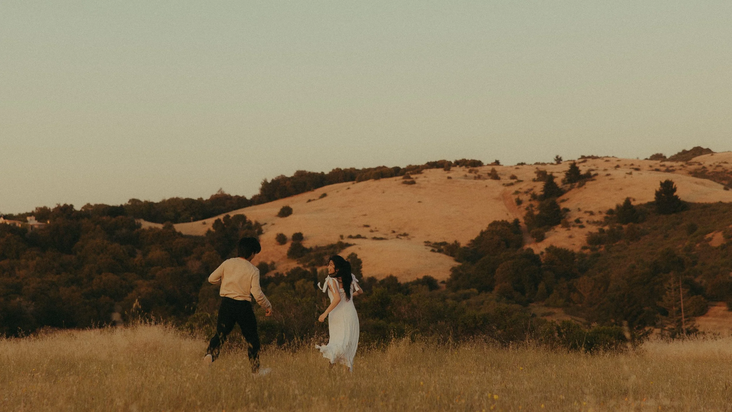 Oahu couples playing in meadow during golden hour