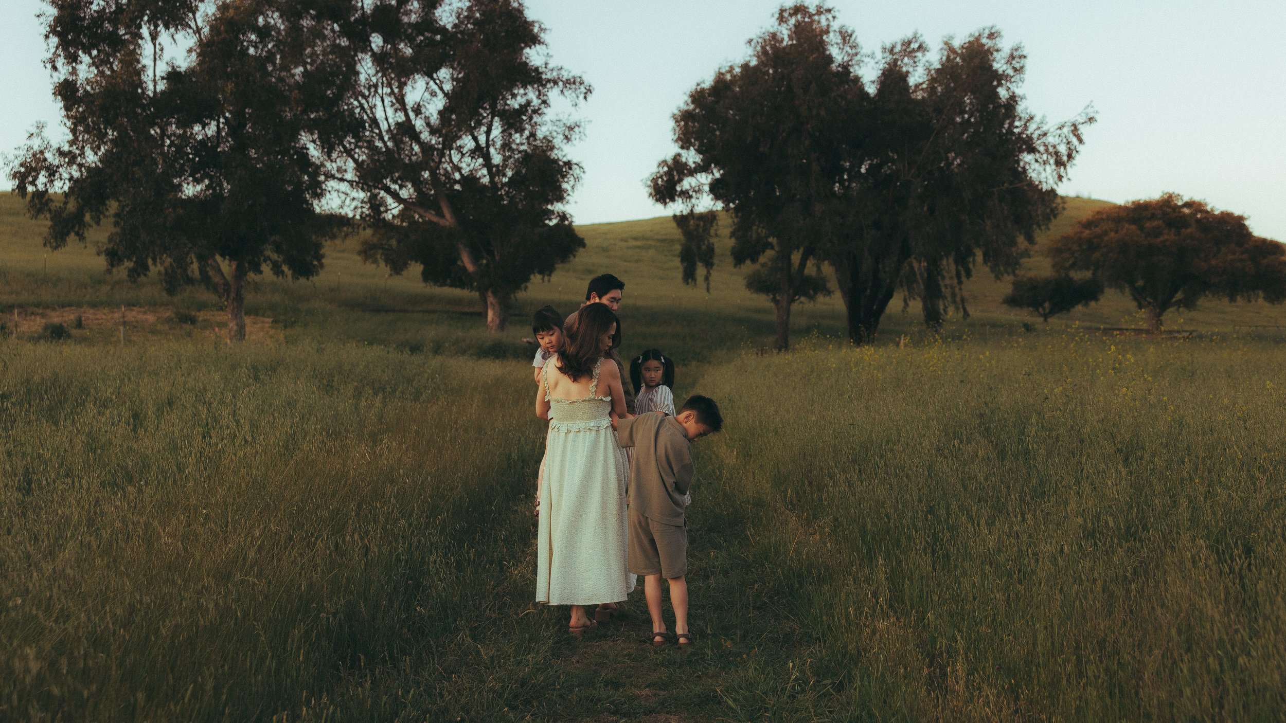 Oahu family photography walking through field at sunset
