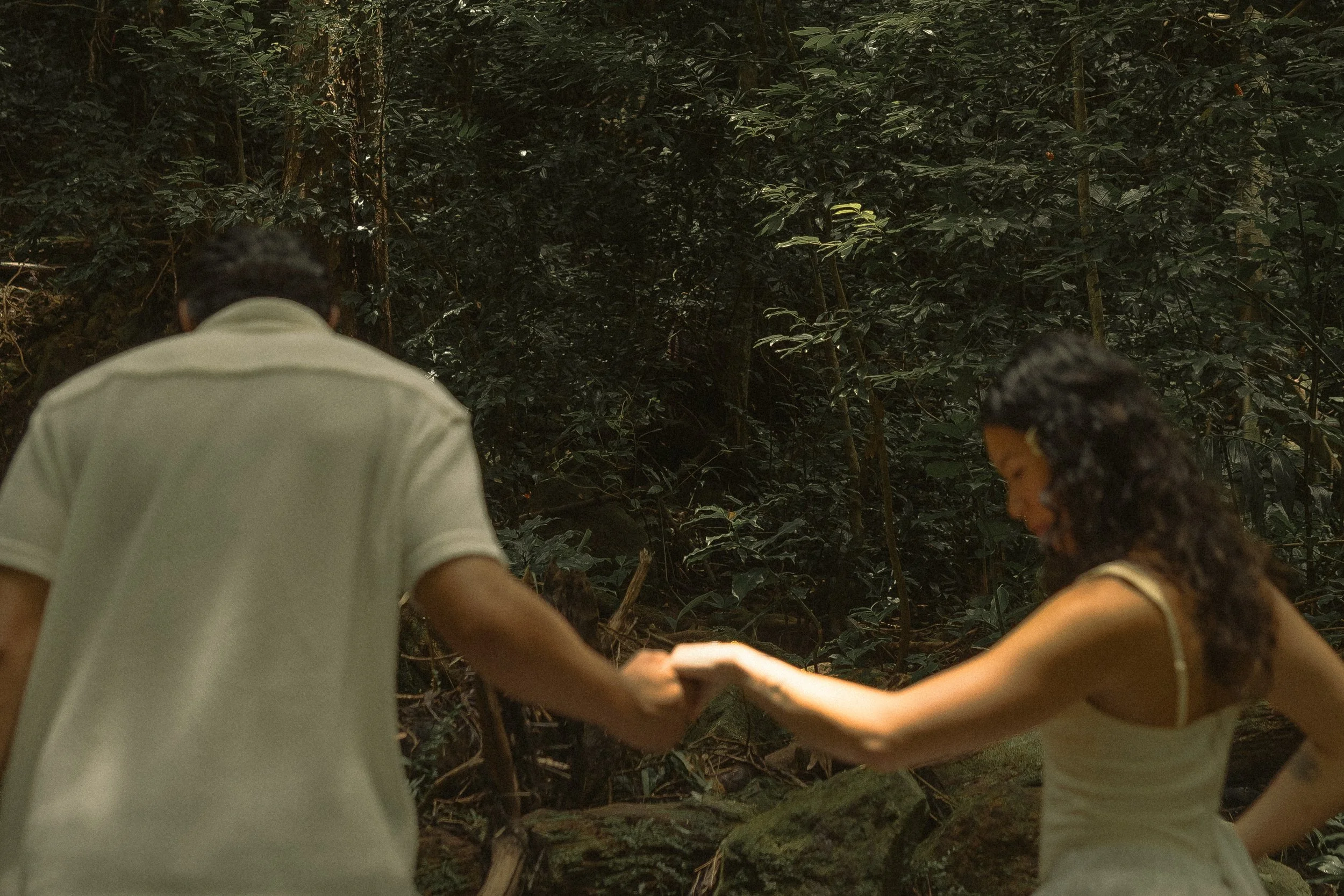 Couple holding hands while exploring a lush jungle forest in Oahu, candid documentary-style couples photography by Maggie T Photography