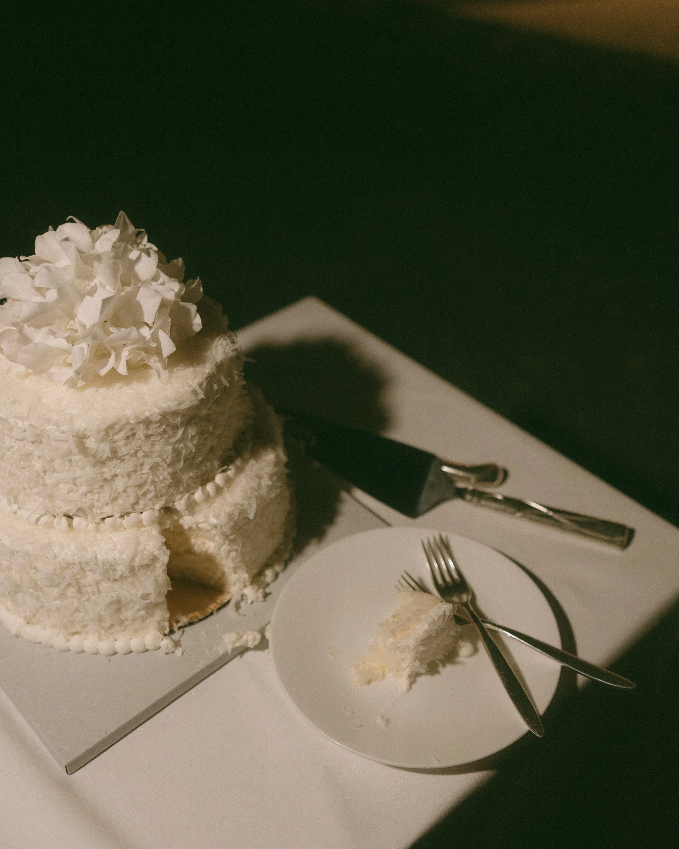 Two-tier coconut wedding cake with a slice cut at Halekulani Hotel Oahu micro wedding reception