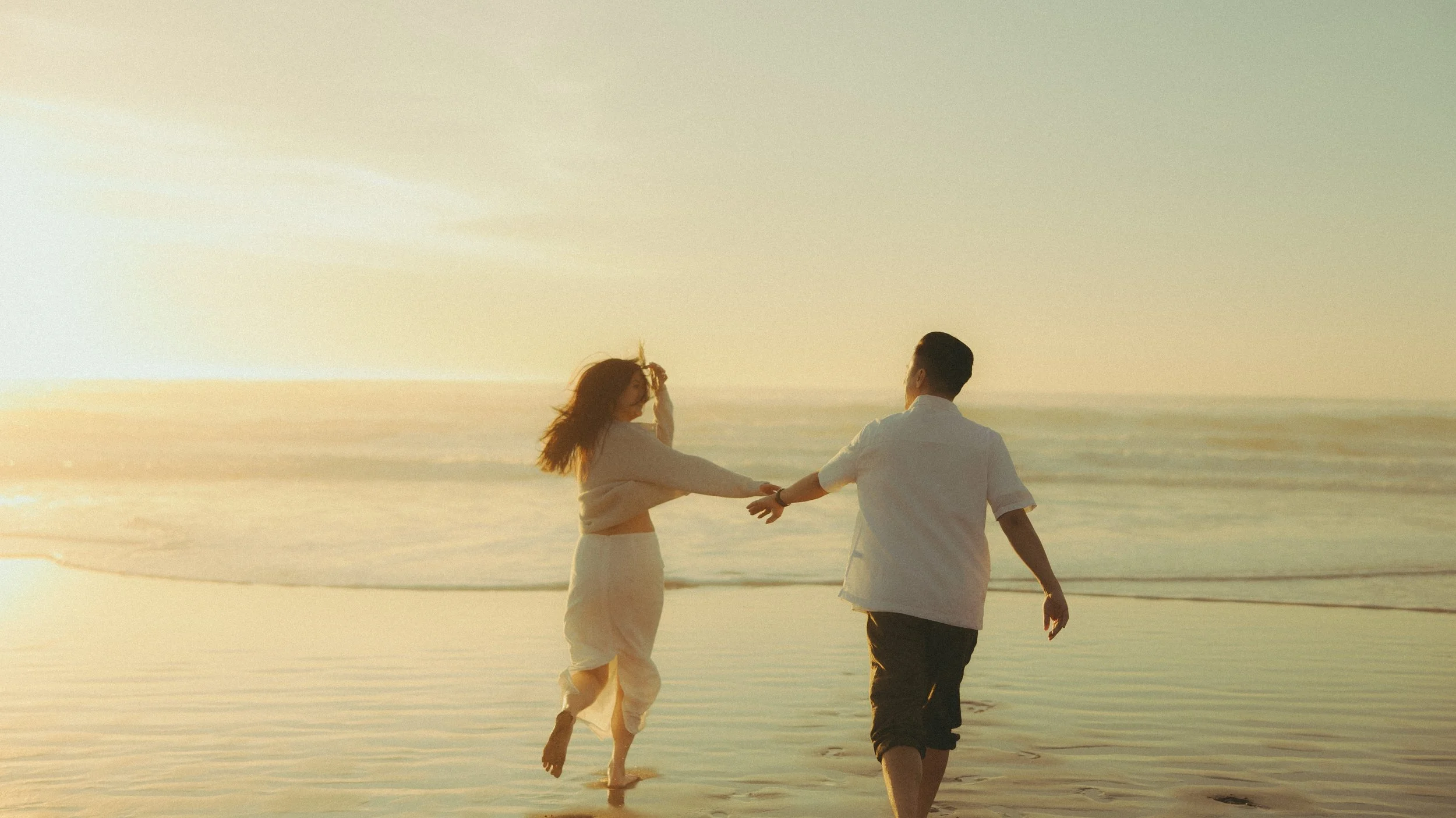 Oahu beach couples walking at golden hour