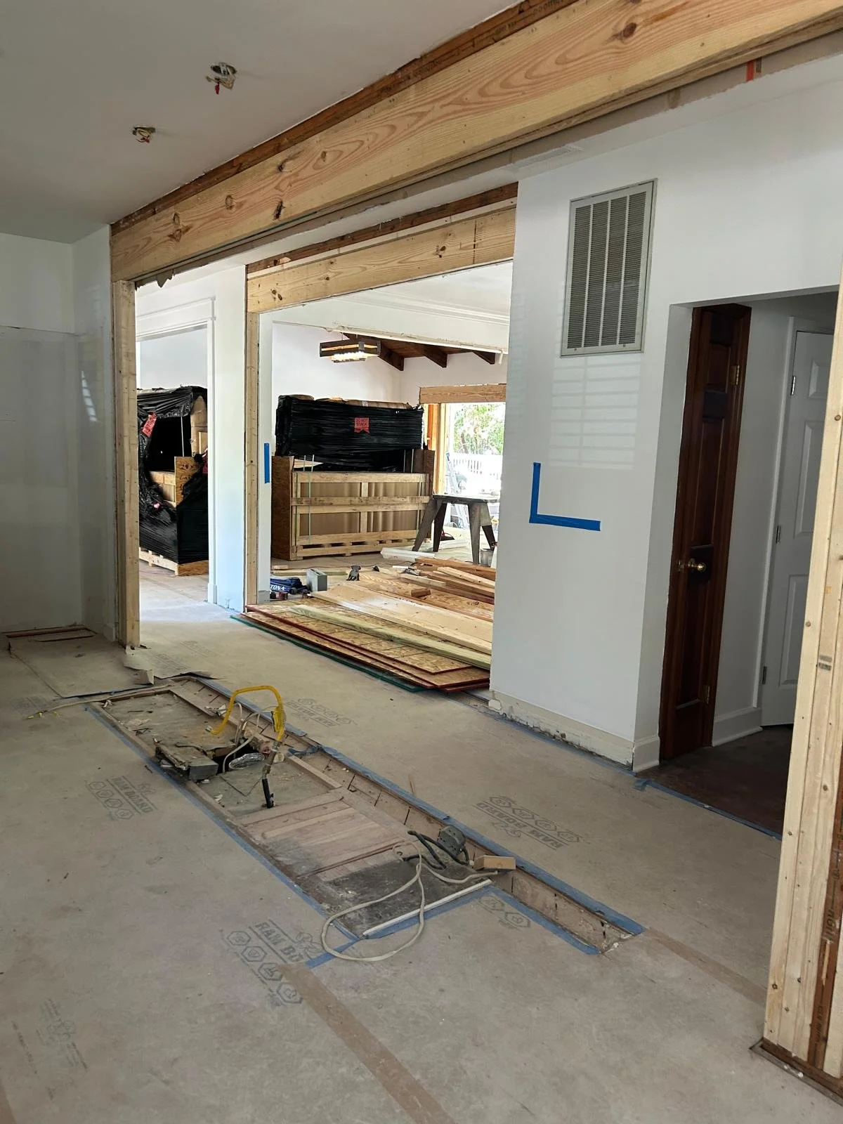 Interior of a house under renovation with exposed wooden beams, construction materials, and partially removed flooring.