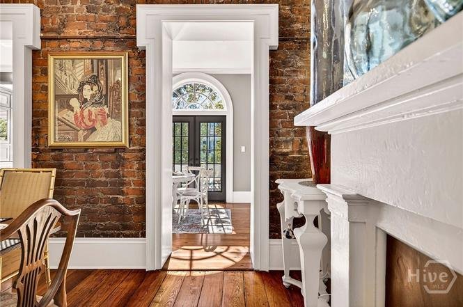 Interior view of a home with brick and white walls, a doorway leading to another room, and wooden furniture.