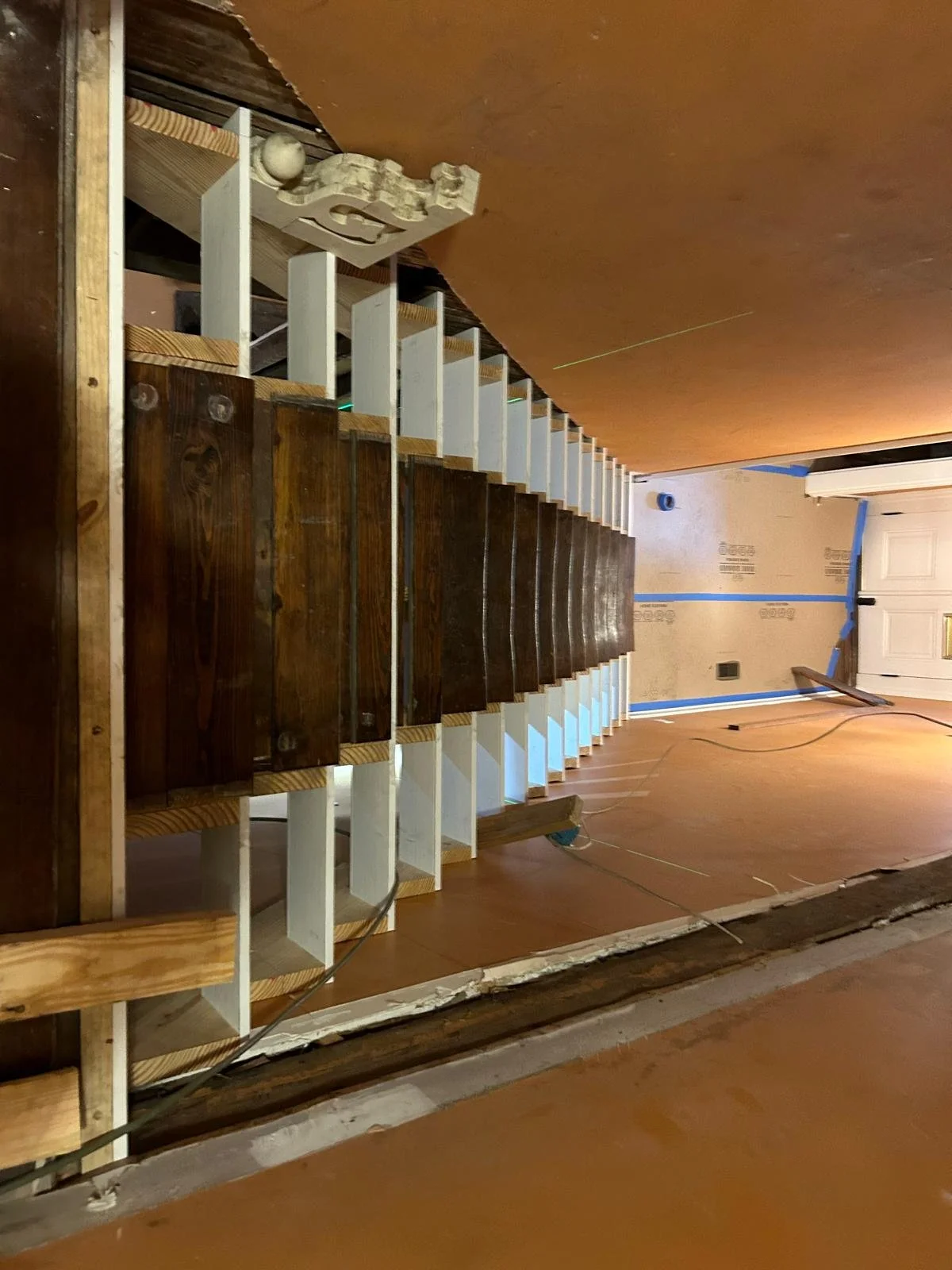 Staircase under construction with wooden steps and white framing in a house renovation site.