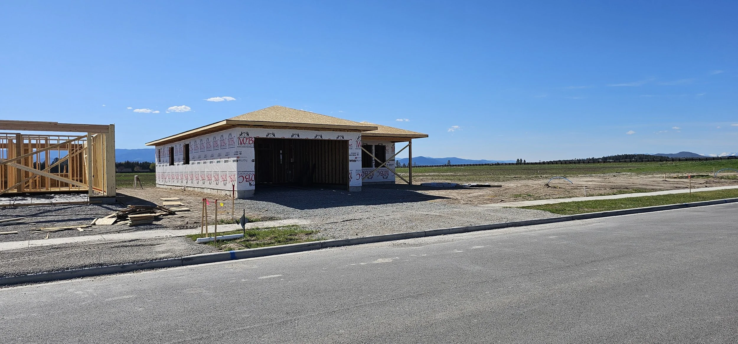Construction site with a small building under construction, wooden framing, and a clear blue sky.