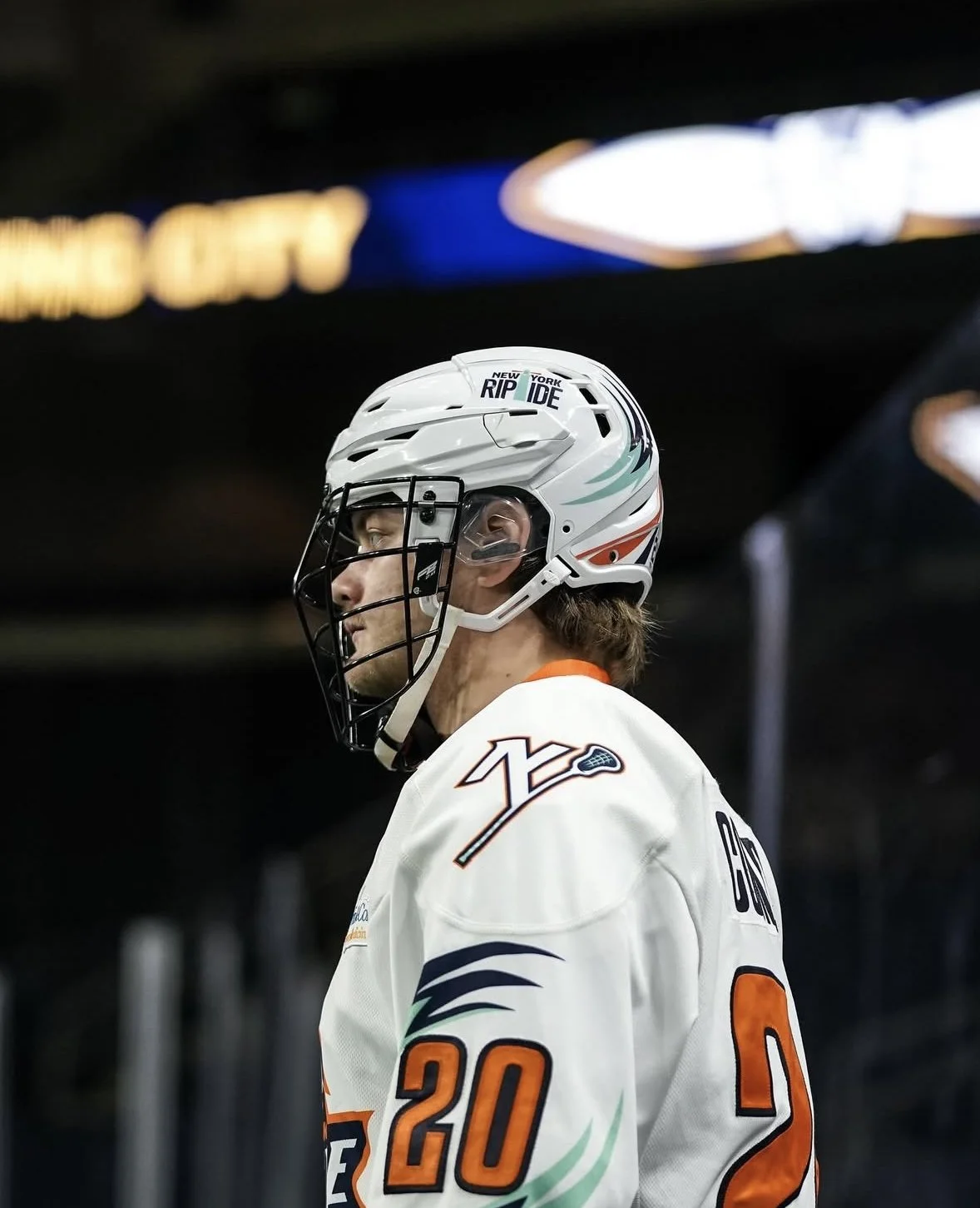 Ice hockey player wearing a white helmet and jersey with the number 20, standing on the ice