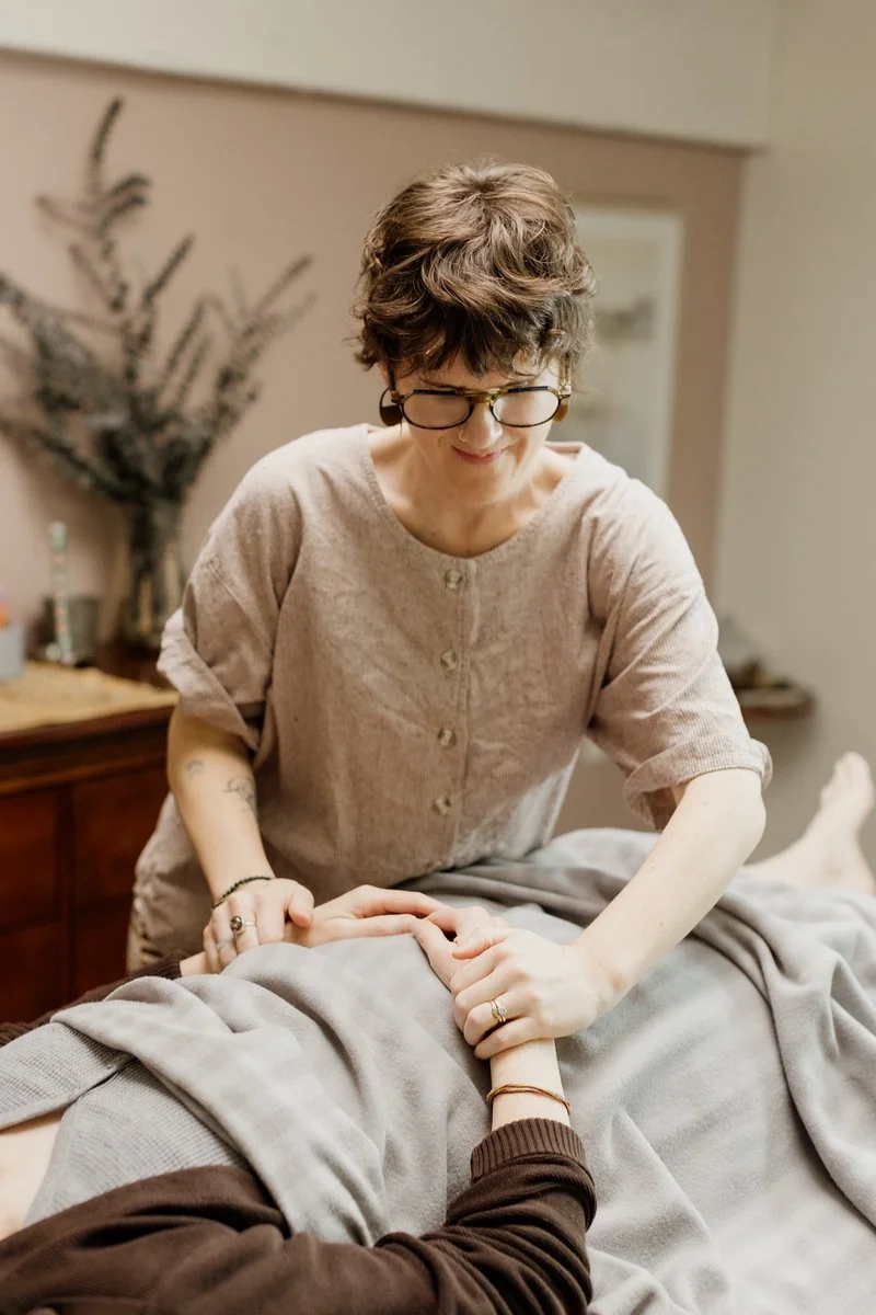 Acupuncturist Kelly Baucum checking the pulse of a patient who is resting comfortable in a reclined position.