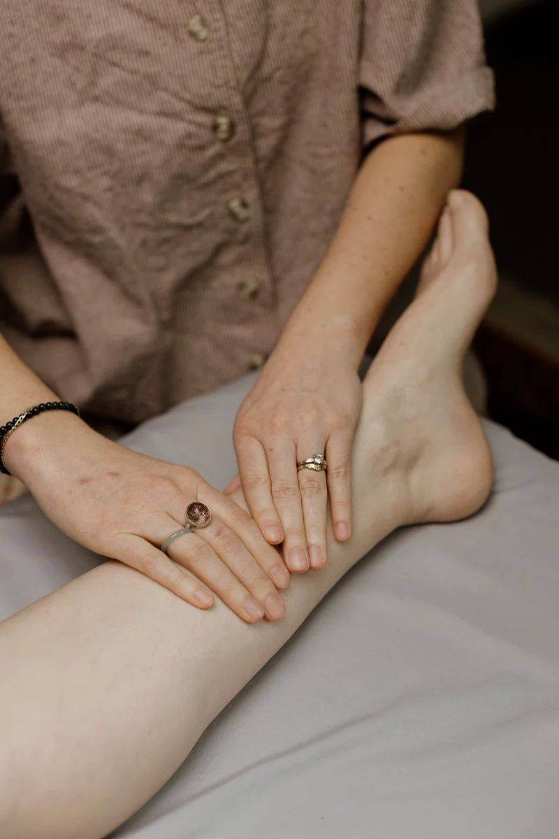 Acupuncturist Kelly Baucum applying gentle acupressure to the inside of a person's ankle.