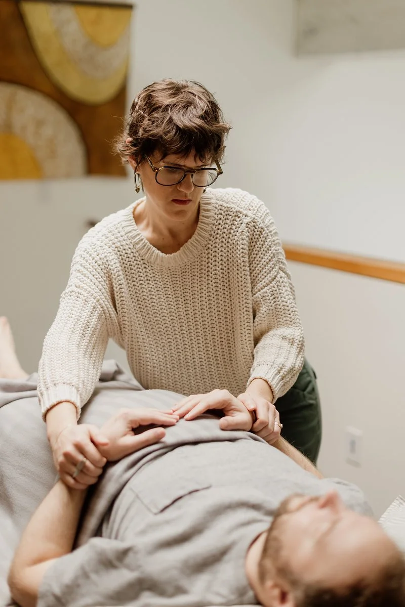 Acupuncturist Kelly Baucum checking the pulse of a patient who is resting comfortable in a reclined position.