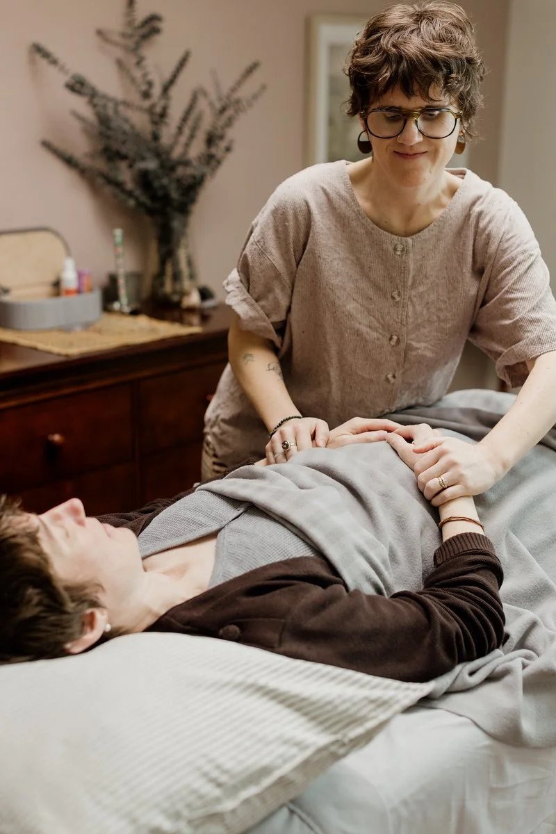 Acupuncturist Kelly Baucum checking the pulse of a patient who is resting comfortably in a reclined position.