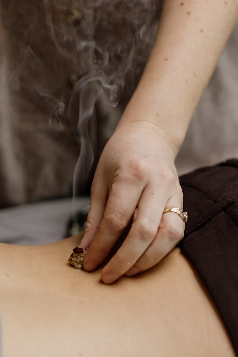 Acupuncturist Kelly Baucum applying gentle moxibustion to a patient's back.