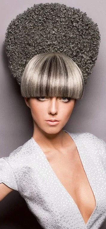 woman with a large, curly, gray afro hairstyle and straight, silver-blonde bangs