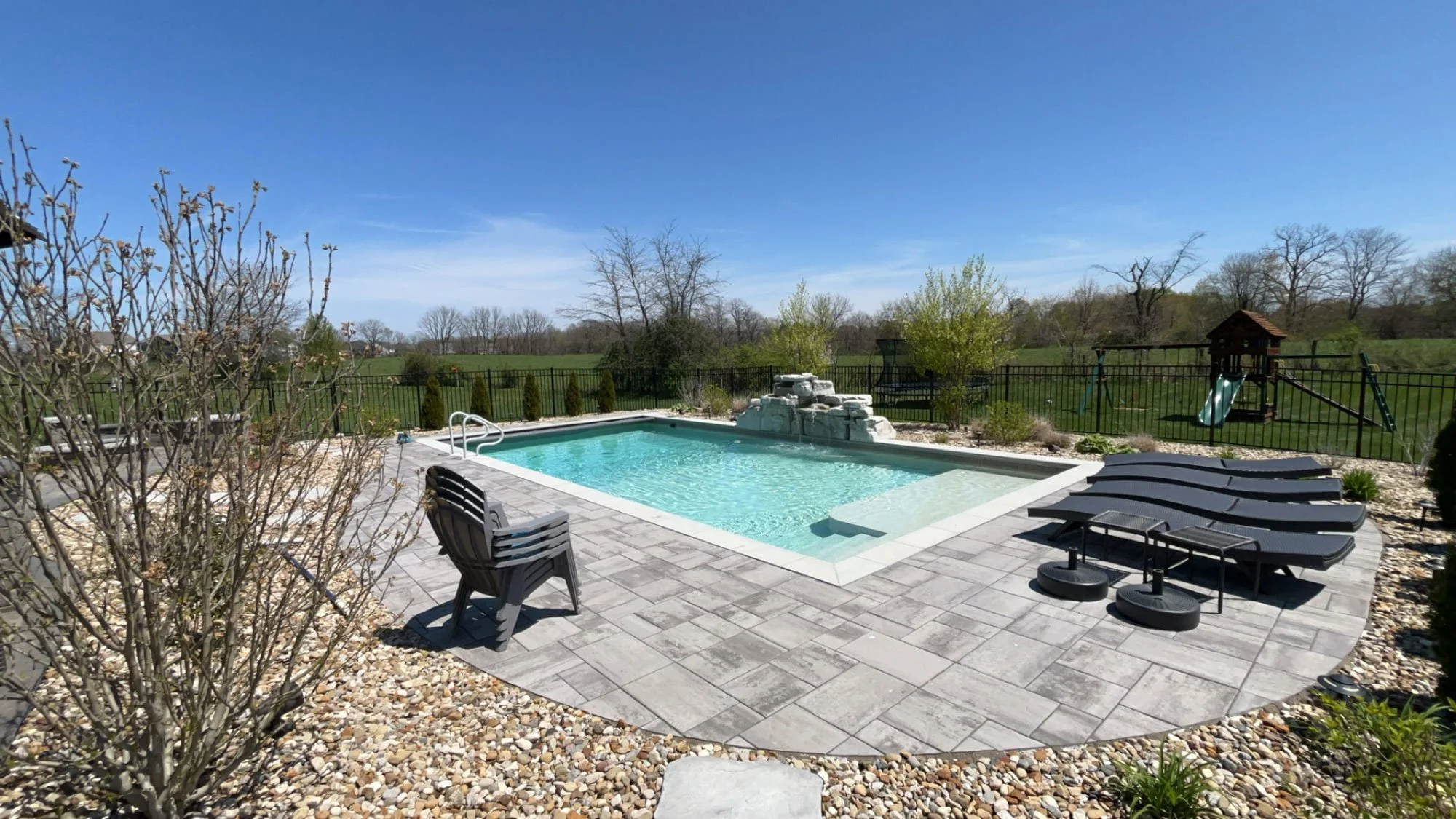 A professionally installed vinyl pool liner with a patterned blue finish, integrated into a massive stone paver patio and modern home exterior.