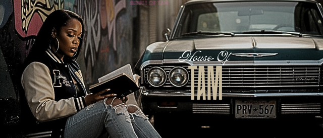 A woman sitting against a graffitied wall, reading a book, with a vintage car parked behind her.