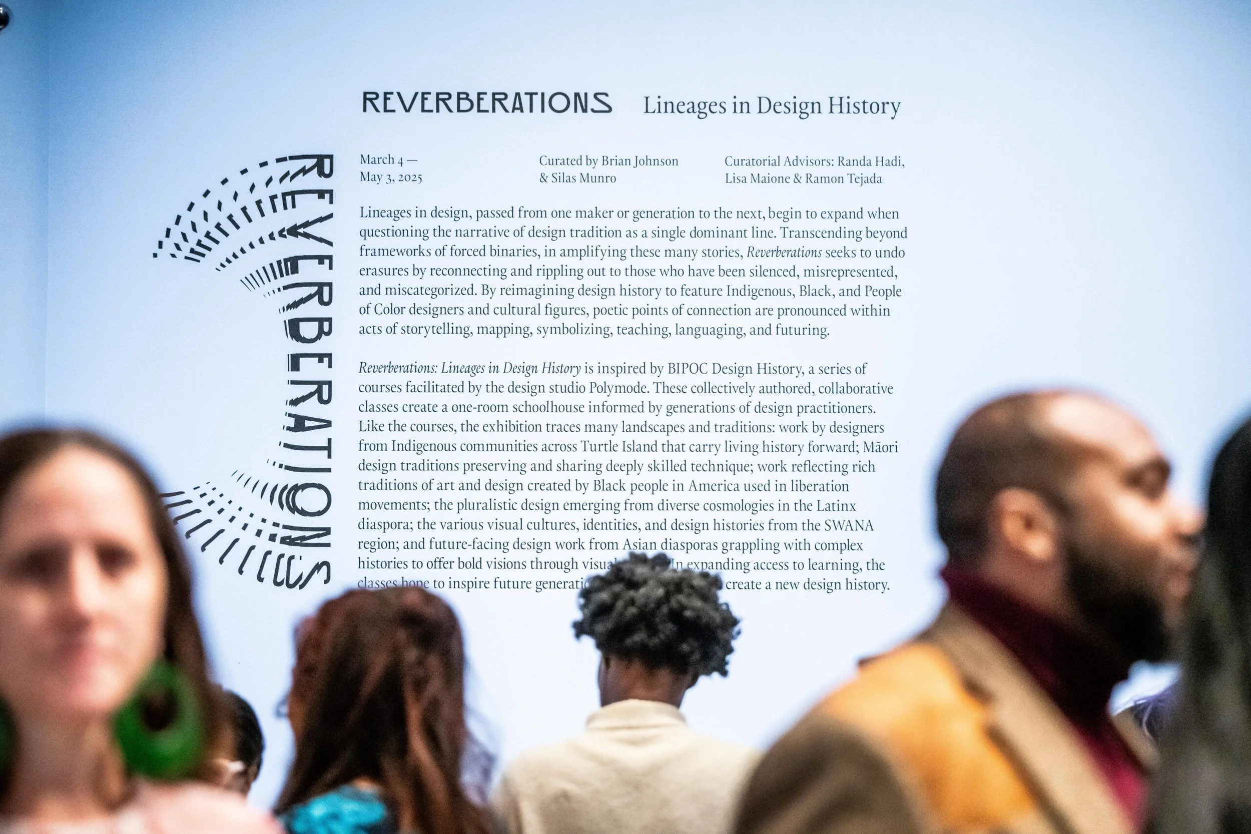 A group of diverse people attending an exhibition or presentation, with a large informational poster behind them titled 'Reverberations: Lineages in Design History'.