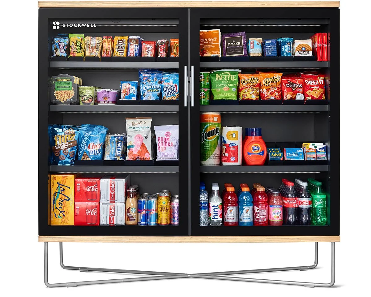 Black storage cabinet filled with snacks, beverages, and household items. Shelves contain chips, candy, soda, and cleaning supplies.